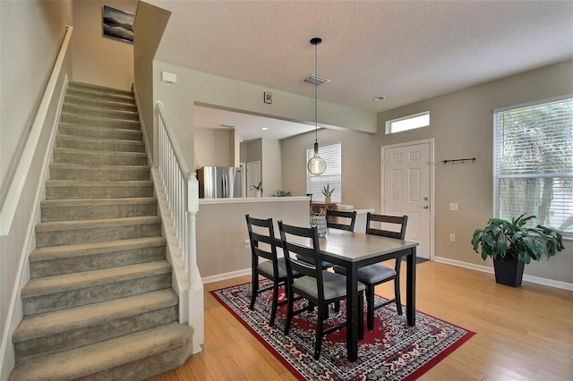 dining space with light wood-type flooring and a textured ceiling