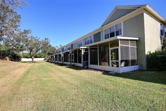 back of house featuring a sunroom and a lawn