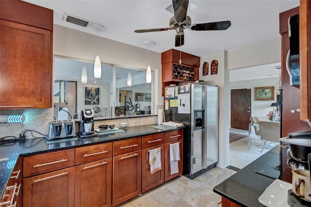 kitchen with hanging light fixtures, dark stone countertops, stainless steel fridge, ceiling fan, and decorative backsplash