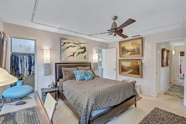 carpeted bedroom featuring a walk in closet, a closet, ceiling fan, and track lighting