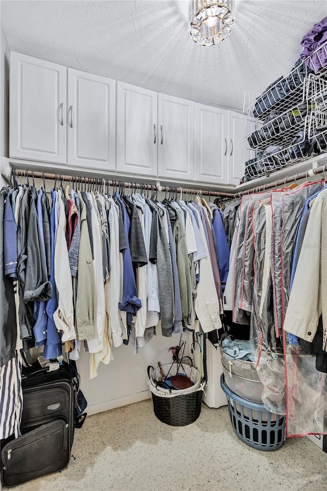 walk in closet featuring a notable chandelier