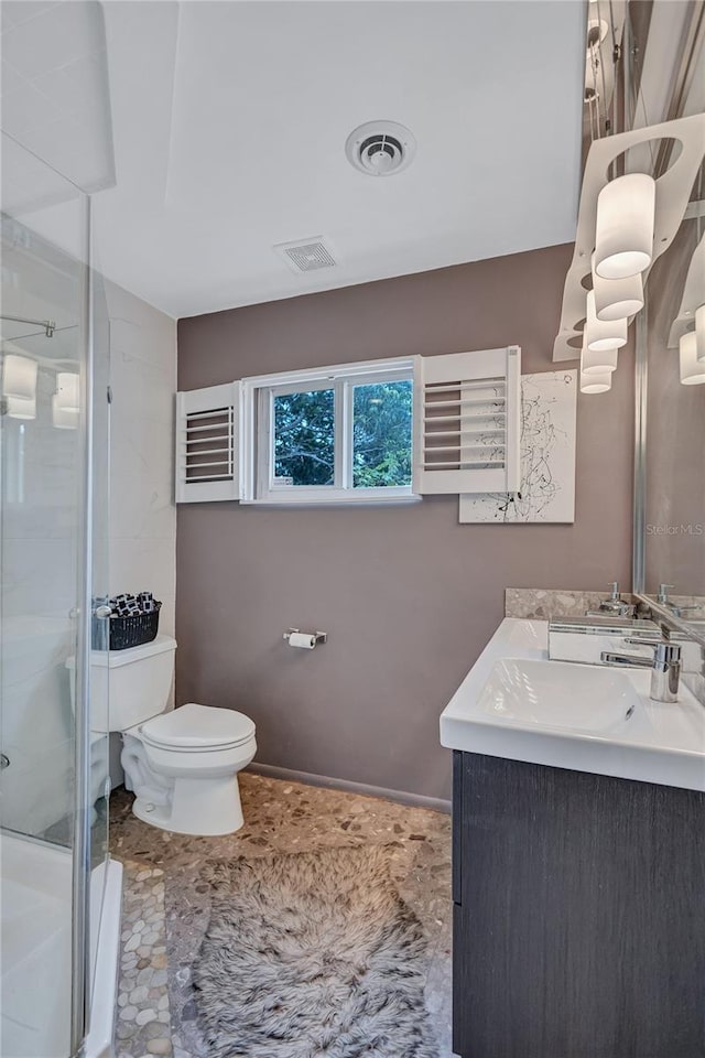 bathroom with a shower with door, vanity, and toilet