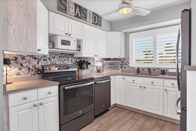 kitchen with appliances with stainless steel finishes, white cabinets, a sink, and backsplash