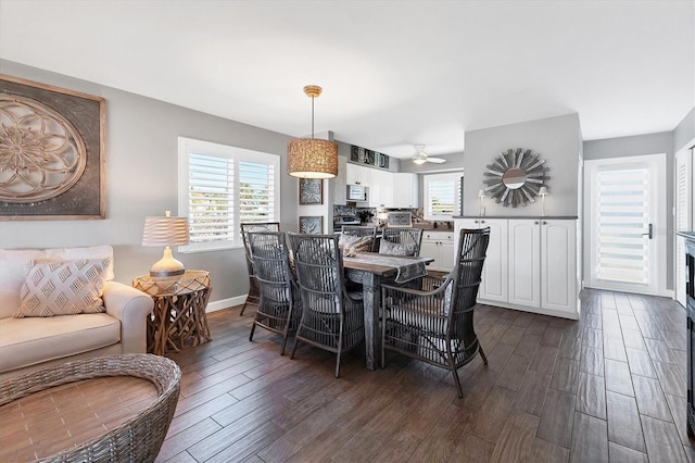 dining space featuring a healthy amount of sunlight, dark wood-style floors, baseboards, and a ceiling fan