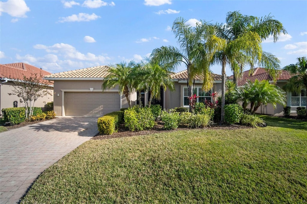 mediterranean / spanish-style home featuring a garage and a front lawn