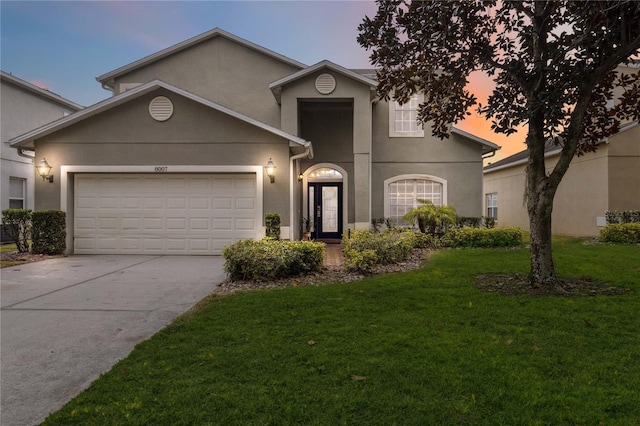 traditional-style home featuring a front lawn, an attached garage, and stucco siding