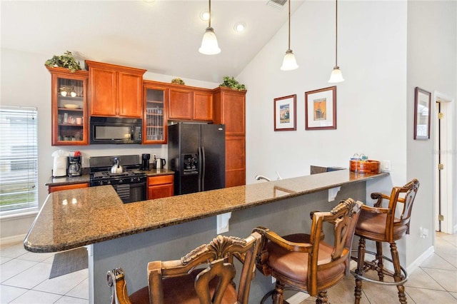 kitchen featuring vaulted ceiling, black appliances, pendant lighting, and a kitchen bar