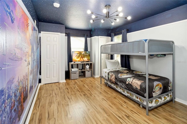 bedroom with a textured ceiling, hardwood / wood-style floors, and a chandelier