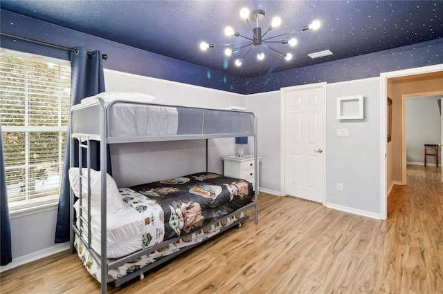 bedroom featuring multiple windows, light hardwood / wood-style floors, and a notable chandelier