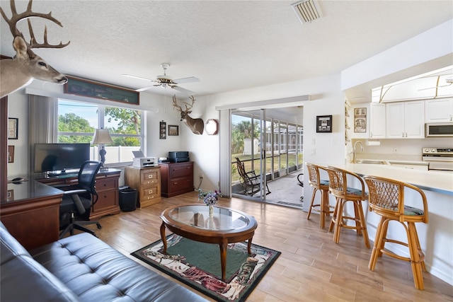 living room featuring sink, a textured ceiling, ceiling fan, and plenty of natural light