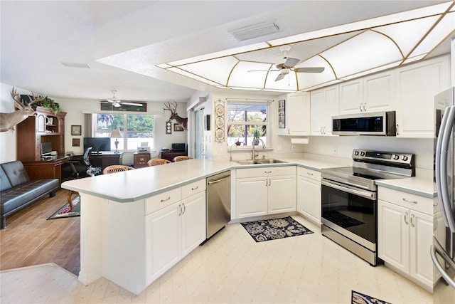 kitchen featuring kitchen peninsula, appliances with stainless steel finishes, white cabinetry, and sink