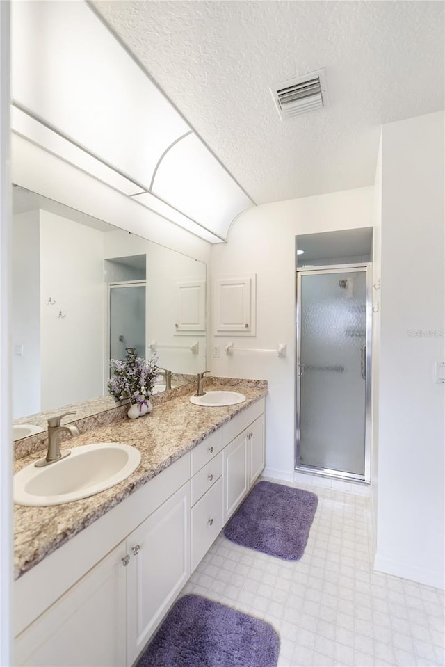 bathroom with an enclosed shower, a textured ceiling, and vanity