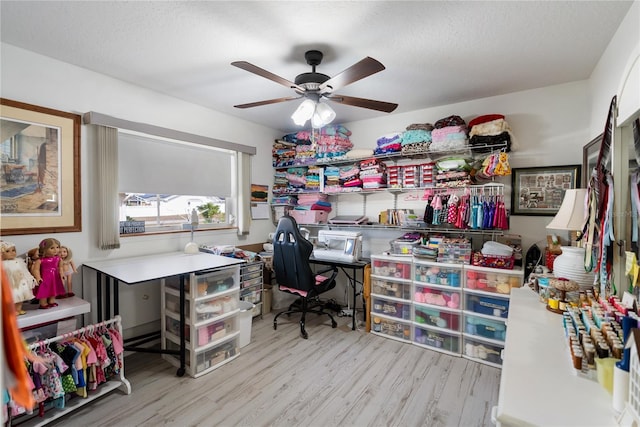 home office with ceiling fan, light hardwood / wood-style flooring, and a textured ceiling