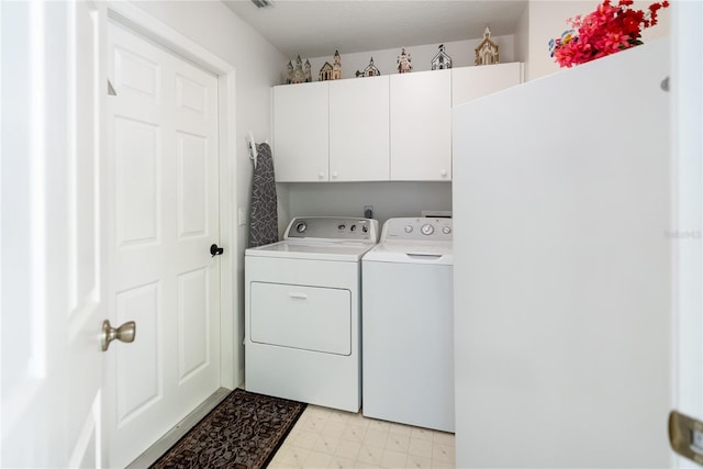 clothes washing area with cabinets and washer and clothes dryer