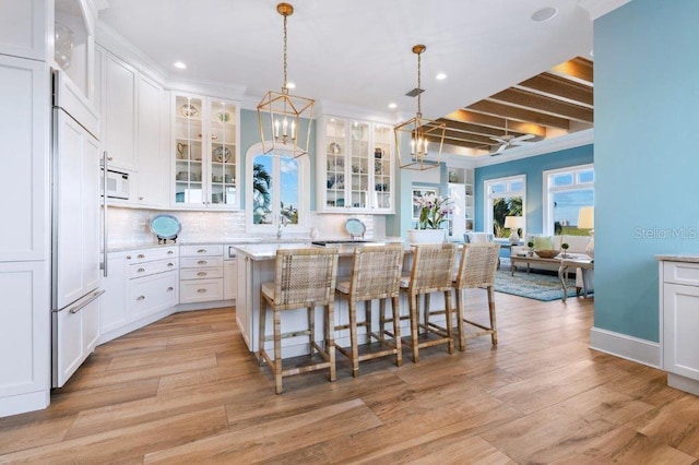 kitchen with a kitchen island, white cabinetry, a kitchen bar, and decorative light fixtures