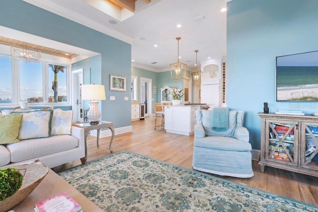 living room featuring light hardwood / wood-style floors, a chandelier, and crown molding