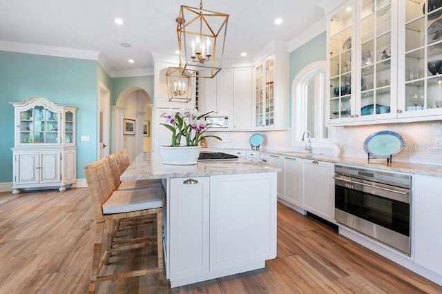 kitchen featuring white cabinetry, light stone countertops, decorative light fixtures, white microwave, and oven