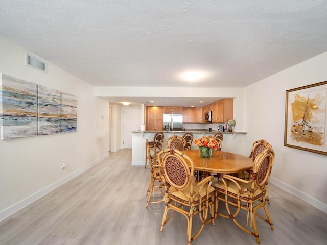 dining area featuring light hardwood / wood-style floors and a textured ceiling