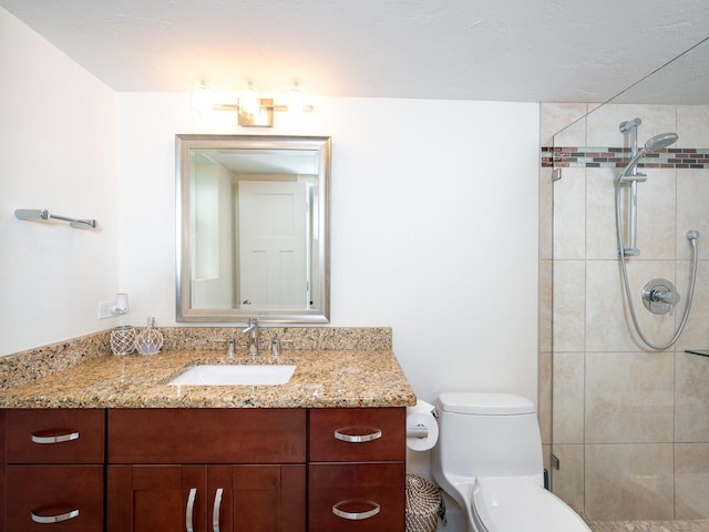 bathroom featuring vanity, toilet, and a tile shower