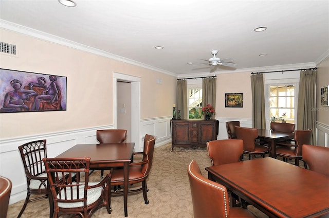 carpeted dining space featuring crown molding and ceiling fan