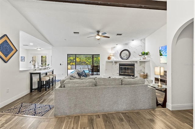 living room featuring ceiling fan, lofted ceiling, a fireplace, and wood-type flooring