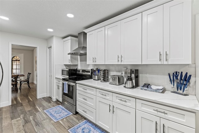 kitchen featuring appliances with stainless steel finishes, dark hardwood / wood-style floors, white cabinetry, backsplash, and wall chimney exhaust hood