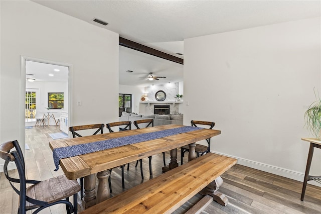 dining area featuring hardwood / wood-style flooring, a wealth of natural light, lofted ceiling with beams, and ceiling fan