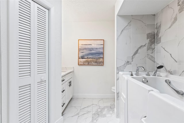 bathroom featuring vanity, a tub to relax in, a textured ceiling, and toilet