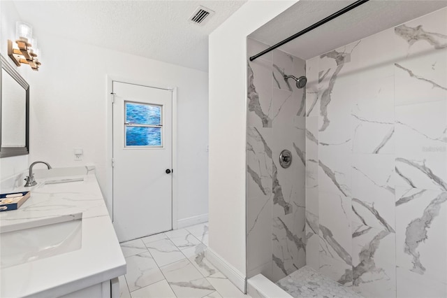 bathroom featuring vanity, a textured ceiling, and a tile shower