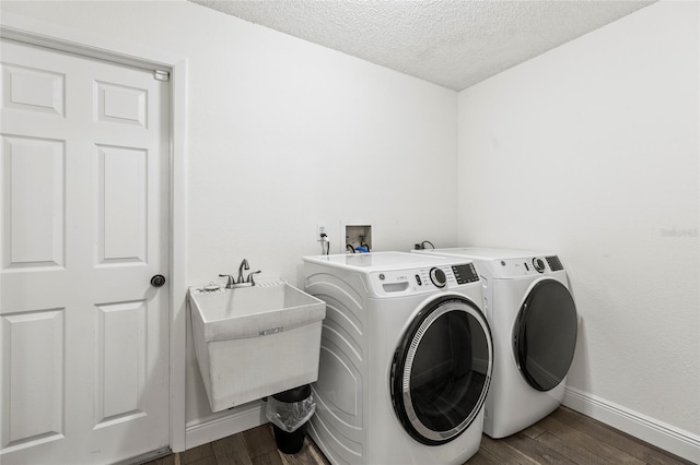 washroom with sink, dark wood-type flooring, washer and dryer, and a textured ceiling