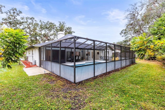 view of swimming pool featuring a patio, glass enclosure, and a lawn