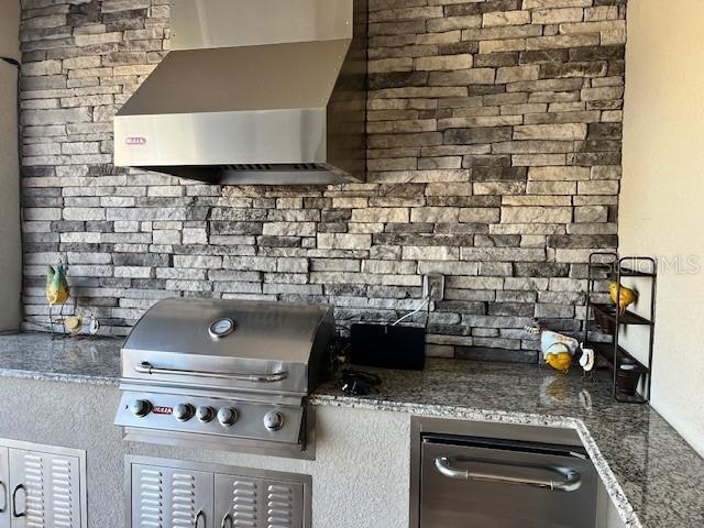 kitchen featuring wall chimney exhaust hood and dark stone counters