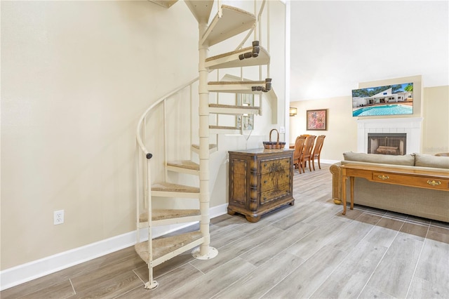 staircase with hardwood / wood-style flooring, a fireplace, and a high ceiling