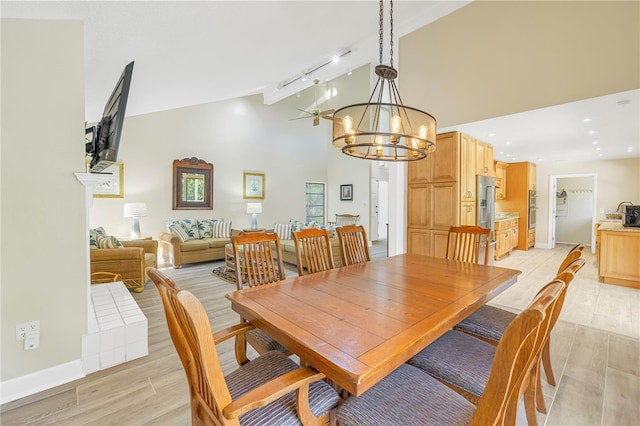 dining area featuring high vaulted ceiling, track lighting, a notable chandelier, and light hardwood / wood-style floors