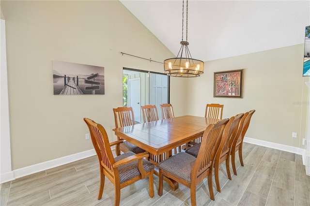 dining area featuring an inviting chandelier, high vaulted ceiling, and light hardwood / wood-style floors