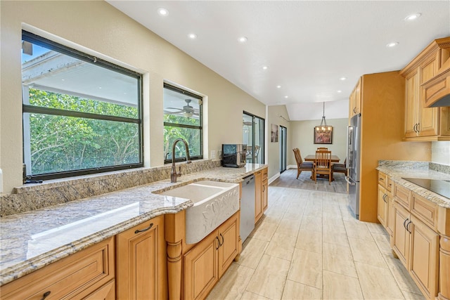 kitchen featuring hanging light fixtures, appliances with stainless steel finishes, sink, and light stone counters