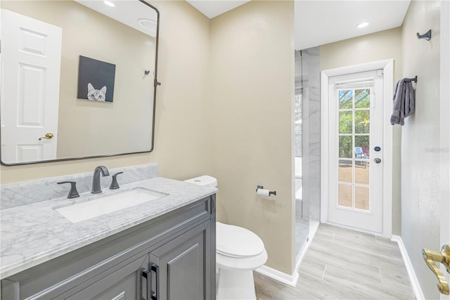 bathroom featuring vanity, walk in shower, and toilet