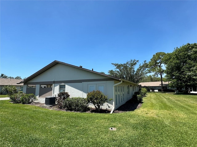 view of side of home with a yard and central AC unit