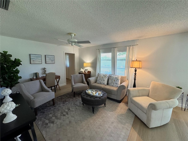 living room featuring ceiling fan, light hardwood / wood-style floors, and a textured ceiling