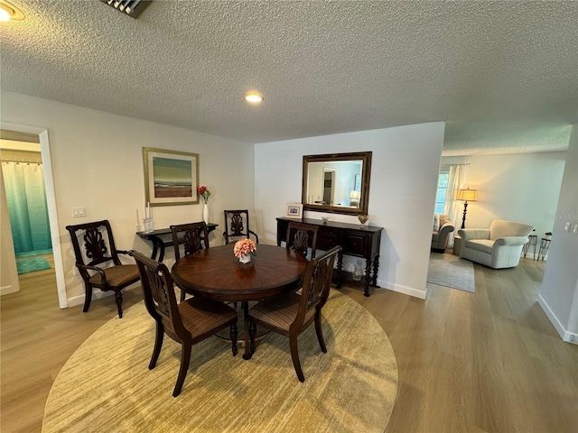 dining space with hardwood / wood-style flooring and a textured ceiling