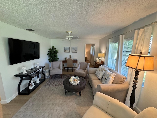 living room featuring light hardwood / wood-style floors, ceiling fan, and a textured ceiling