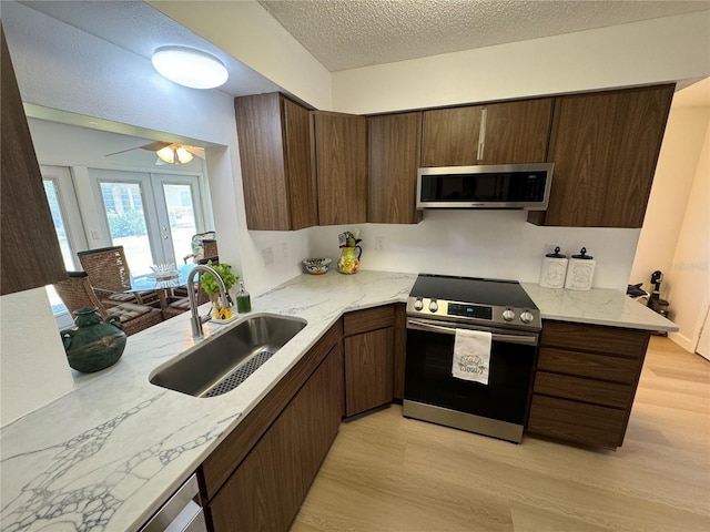 kitchen with stainless steel appliances, sink, a textured ceiling, light hardwood / wood-style floors, and kitchen peninsula