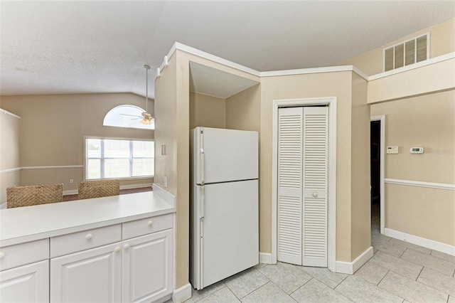 kitchen with white fridge, light tile patterned floors, ceiling fan, white cabinetry, and lofted ceiling