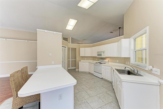 kitchen with white appliances, a kitchen bar, white cabinets, lofted ceiling, and sink