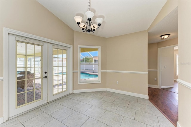 interior space with lofted ceiling, french doors, a chandelier, and light tile patterned floors