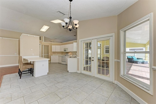 kitchen with white cabinetry, a center island, french doors, white appliances, and a notable chandelier