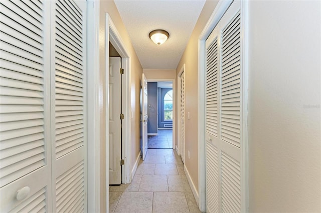 hall featuring a textured ceiling and light tile patterned floors