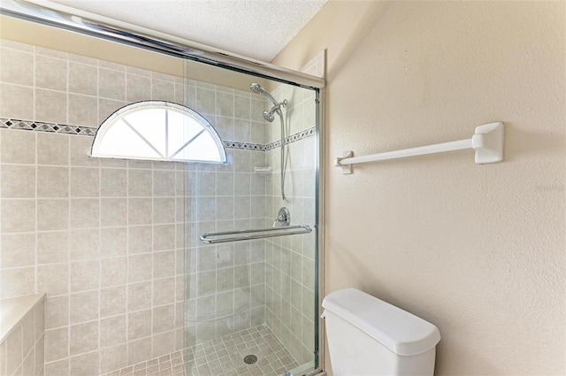 bathroom featuring toilet, walk in shower, and a textured ceiling