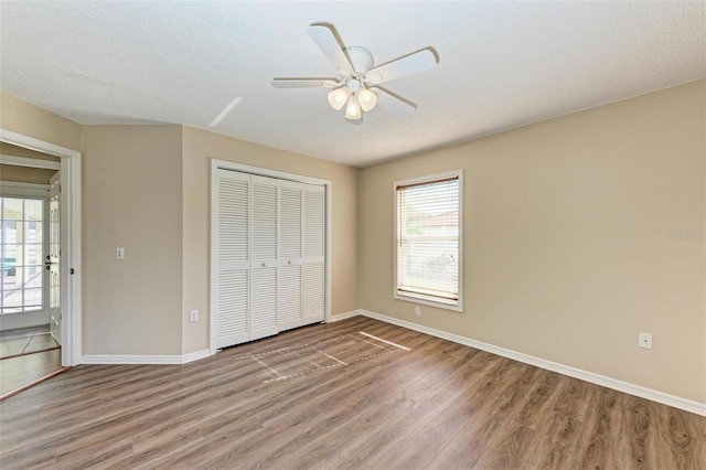 unfurnished bedroom with wood-type flooring, multiple windows, a closet, and ceiling fan