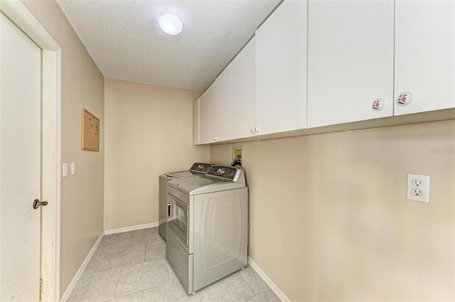 laundry area with washer / clothes dryer, a textured ceiling, and cabinets